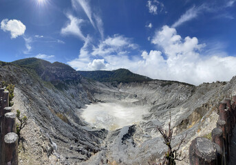 Majestic View of a Volcanic Crater in Tangkuban Perahu, Indonesia, Surrounded by Lush Hills Under a Clear Blue Sky