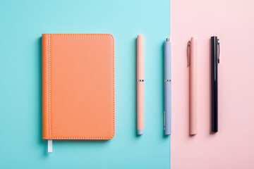 Notebook and pens resting on a two toned surface, embracing pastel hues