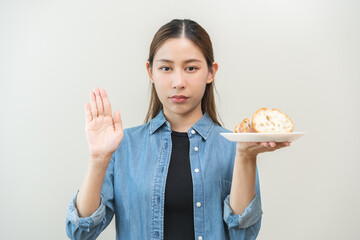 Gluten allergy, asian young woman hand push out, refusing to eat white bread loaf on plate in...