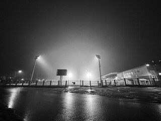 The football stadium is illuminated by lanterns during soccer practice at night during fog