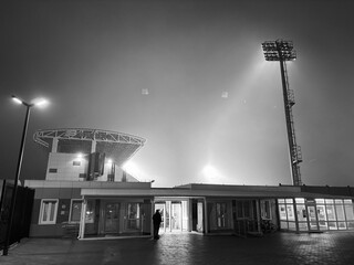 The football stadium is illuminated by lanterns during soccer practice at night during fog	