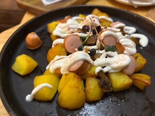 a delicious dish of fried potatoes and fried sausages with mayonnaise on a baking sheet in a restaurant