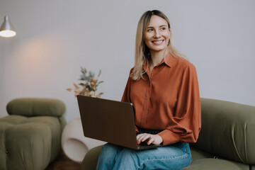Young woman working on laptop in modern indoor space during daytime with a warm smile