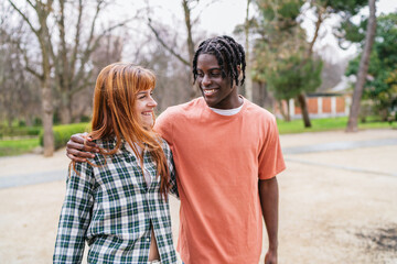 Obraz premium Happy multiracial young couple walking and smiling in park