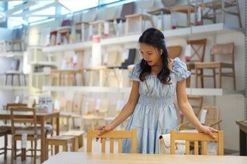 asian woman shopping for wooden furniture in store