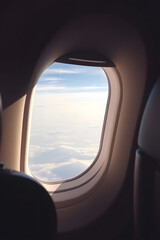 View from an airplane window showing clouds and sunlight.