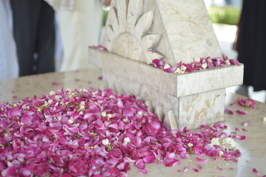 a marble tomb decorated with pink and white flower petals, with people standing nearby.