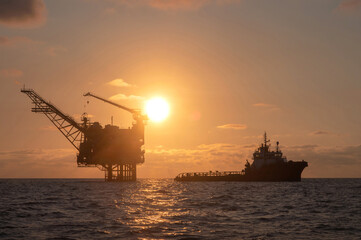 Obraz premium Beautiful image of offshore gas drilling rig as the sun rises in the morning, with service boats approaching.
