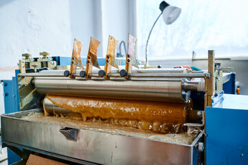 Innovative glue-spreading machine in action, applying hot glue with precision in a workshop...