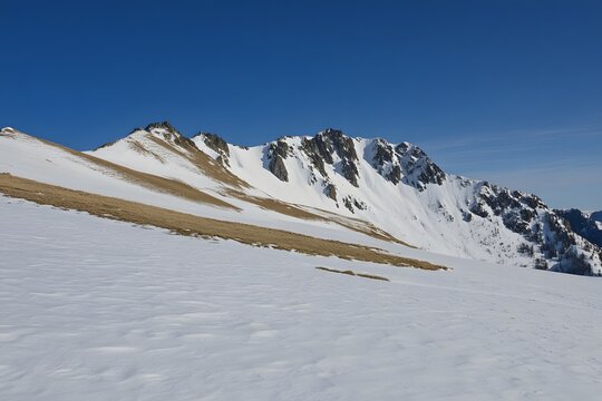 Snowy mountain range under a clear blue sky on a bright sunny day