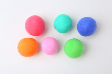Different colorful play dough balls on white background, flat lay