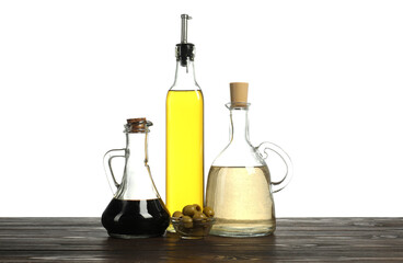 Salad dressings and olives on wooden table against white background