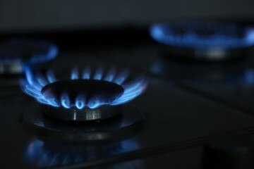Gas burners with blue flame on stove, closeup