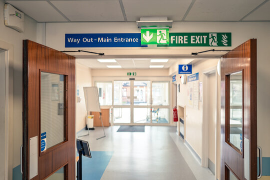 Shallow focus of a typical illuminated Fire Exit sign seen within an NHS hospital outpatients department. The fire exit leads to the car park and the AE department.
