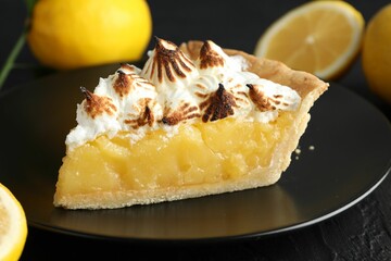 Piece of delicious pie with browned meringue on black textured table, closeup