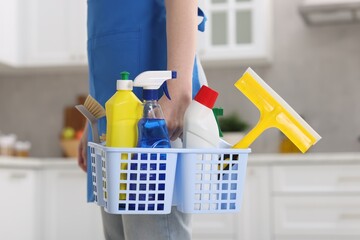 Woman with basket of cleaning supplies at home, closeup
