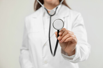 Doctor with stethoscope on light background, closeup