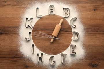 Clock made with flour, kitchen utensils and letter shaped cookie cutters on wooden background, top...