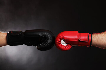 Men in boxing gloves fighting on dark background with smoke, closeup