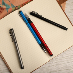 Elegant Pen Standing on Open Notebook with Vivid Decorative Backdrop, concept idea photo. Study desk image, top view.