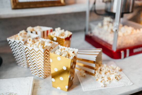 Popcorn in gold-wei&szlig;en Papiert&uuml;ten an einer Popcornmaschine