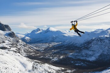 Ziplining thrill person soars over snowy mountains on steel cable