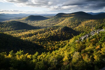 Obraz premium Autumn valley view hill peaks touched by sunlight and dramatic clouds