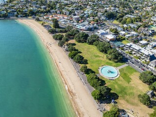 Aerial view of Mission Bay Beach in Auckland, New Zealand. People are enjoying the beach, park, and...