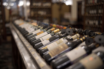 Fototapeta premium Row of wine bottles with dry red and white wine on wooden. Low depth of field.