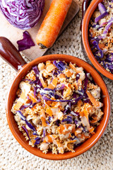 Colorful vegan cous cous with chickpeas, purple cabbage and carrots. Topping of tahini and flax seeds.
