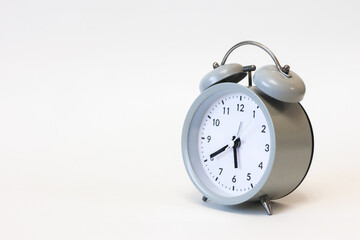 Classic black and white analog alarm clock on a plain white background, showing time clearly, symbolizing punctuality and timeless design.