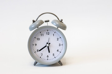 Classic black and white analog alarm clock on a plain white background, showing time clearly, symbolizing punctuality and timeless design.