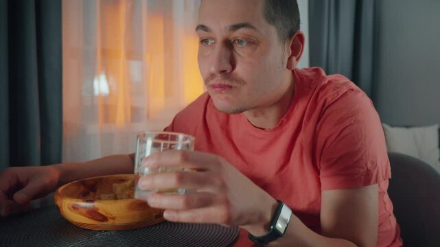 A man in a casual red shirt sits at a table, savoring his meal served in a wooden bowl