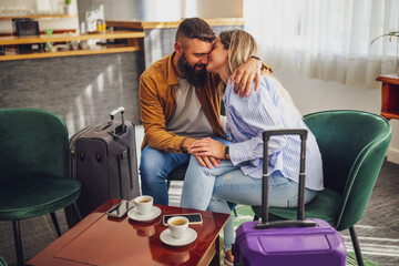 Loving couple sitting in hotel lobby and embracing.