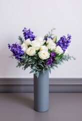 A beautiful floral arrangement displaying white roses and vibrant purple flowers, set in a sleek gray vase, exuding sophistication, freshness, and elegance. Ideal for decor, gifting, or celebrating sp