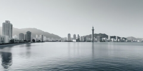 Fototapeta premium Black and white panoramic view of a city along the water, backed by hills.