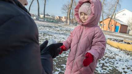 Grandfather playing with her granddaughter on the playground in the park in winter