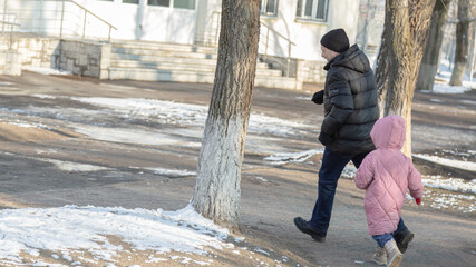 Grandfather playing with her granddaughter on the playground in the park in winter