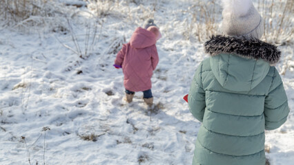 Children walk in a winter snowy forest. Frosty sunny day.