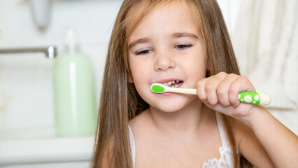 little girl brush her teeth in a bathroom