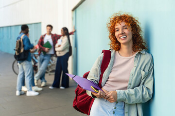 Smiling portrait of red-haired girl studying at university ready to start academic classes
