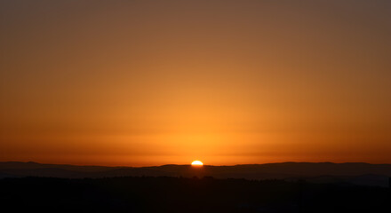 Fototapeta premium Magnificent sunset panorama with vivid orange gradient sky over silhouette mountains