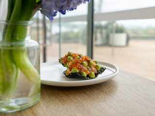 White plate, set on a wooden table near a window with natural light. The dish consists of crispy...
