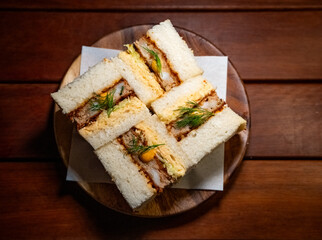 Japanese-style sandwiches, katsu sando. The sandwiches are made with thick slices of soft, white bread (shokupan) and filled with a crispy, deep-fried cutlet—likely pork or chicken katsu. 