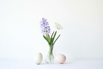 Elegant spring floral arrangement with purple and white flowers in a clear vase alongside pastel eggs, embodying the essence of Easter and seasonal renewal
