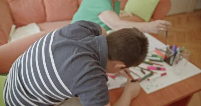 A young boy and his grandmother spend quality time together drawing and knitting, showcasing the beauty of inter generational connection.