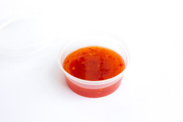 Sweet chilli sauce in a plastic cup isolated on white from above.