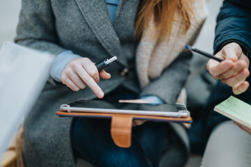 A group engaging in teamwork, analyzing information with a tablet and written documents for a collaborative discussion in a business or educational setup.