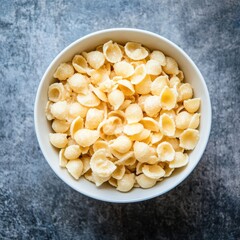 Overhead shot of creamy shell pasta in a white bowl on grey backdrop
