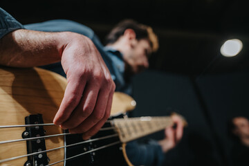Obraz premium Close-up of musician playing electric bass guitar during band rehearsal